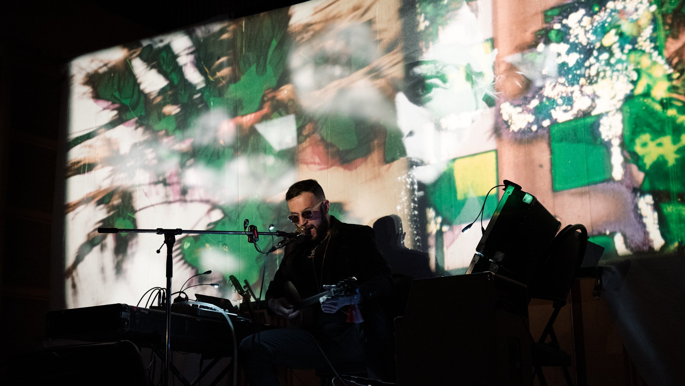 A musician plays an instrument in front of a screen with projected image